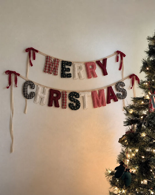 Letterine imbottite in tessuti natalizi per scrivere merry Christmas o buon Natale. Allineate su corda con fiocchi in velluto alle estremità 