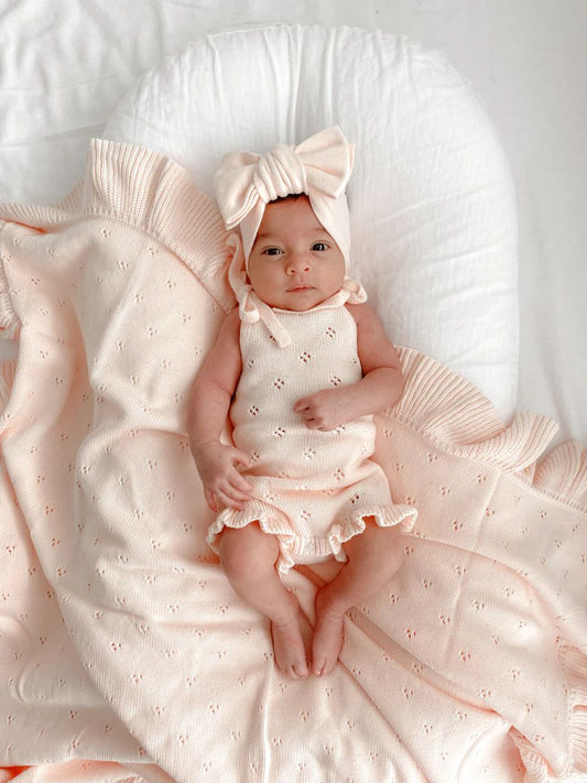 Copertina in cotone organico rosa con lavorazione traforata e bordatura a volant