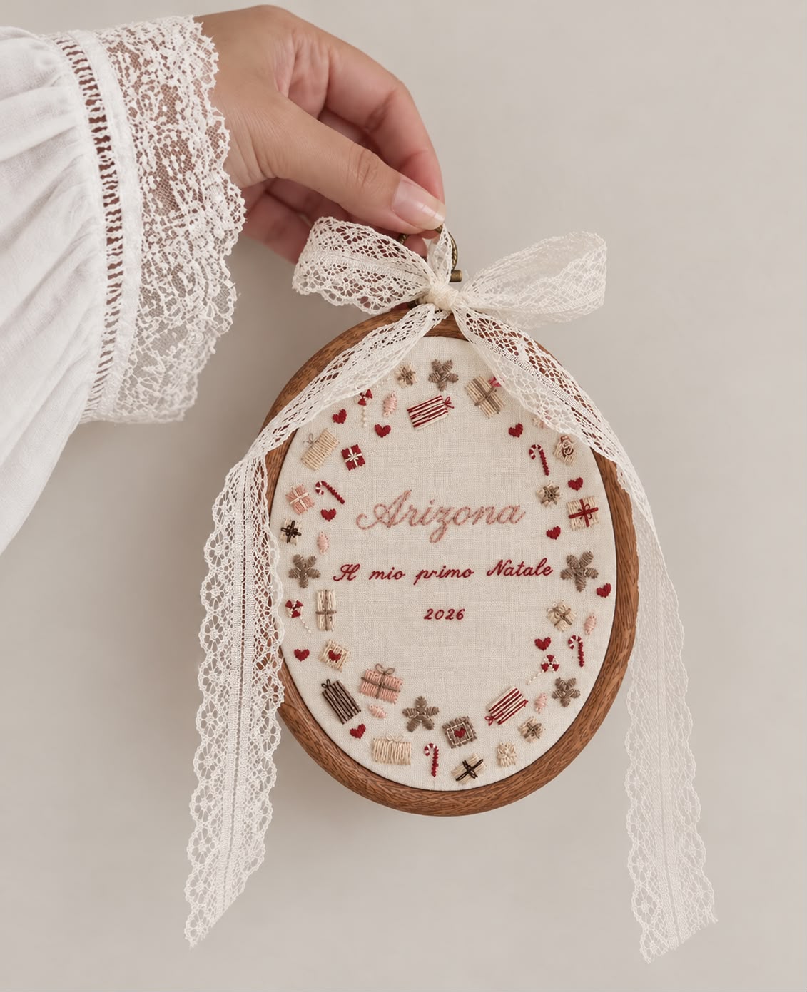 Quadretto da ricamo ovale ricamato con nome e piccola dedica natalizia. Decorato su tutto il bordo con pacchettini regalo e dolcetti di Natale