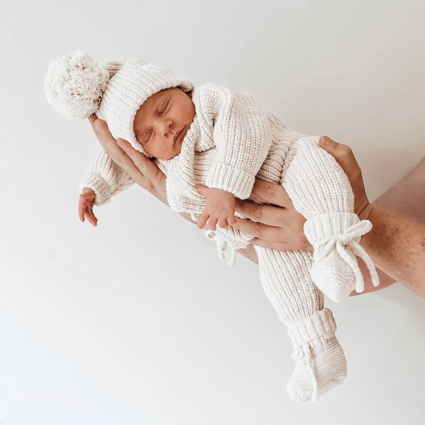 neonato che riposa con indosso il set latte (tutina, cappellino e babbucce) di Ricamo Mini Me