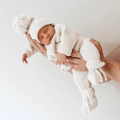 neonato che riposa con indosso il set latte (tutina, cappellino e babbucce) di Ricamo Mini Me