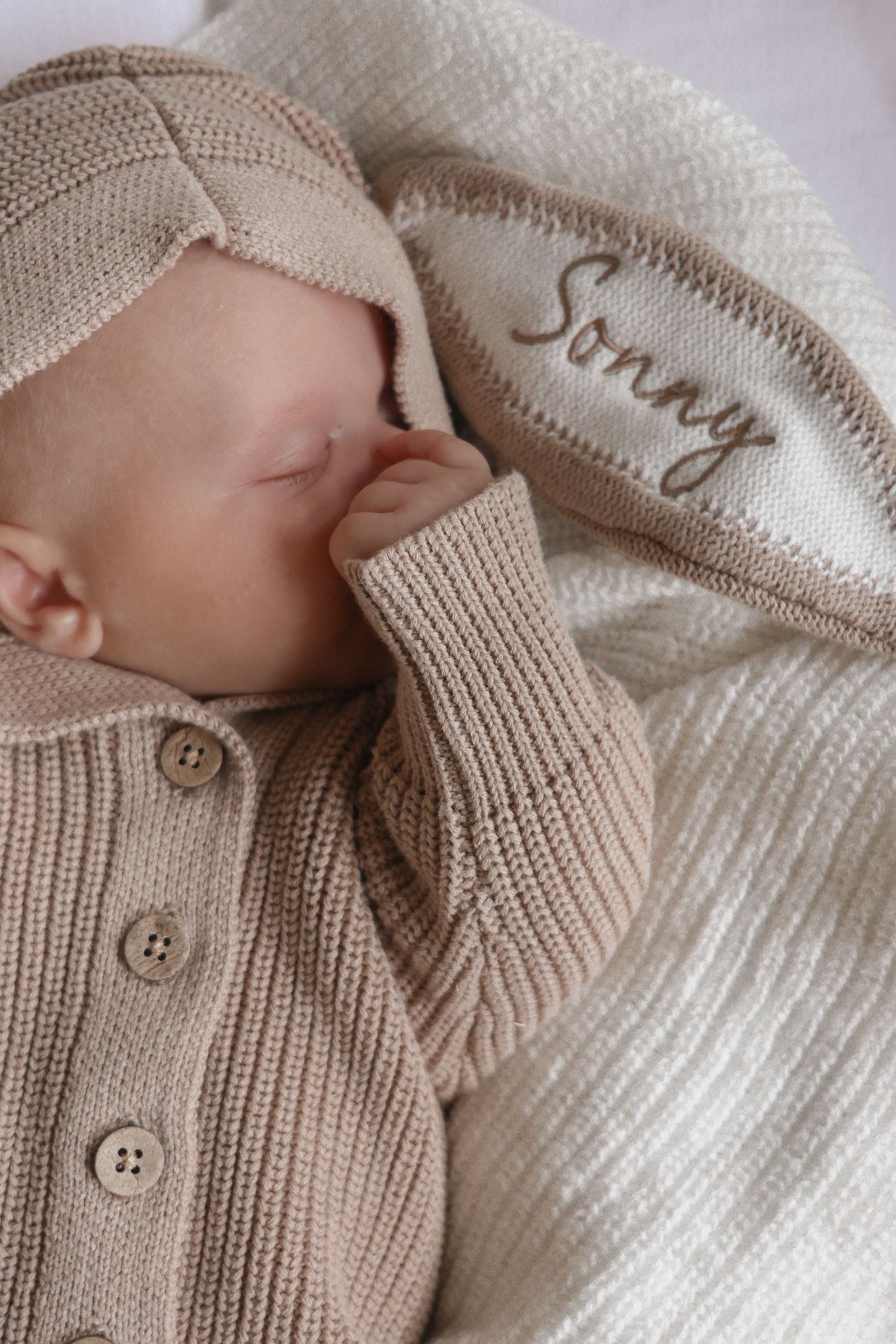 Dettaglio del nome ricamato sul cappuccio della tutina con orecchie da coniglietto