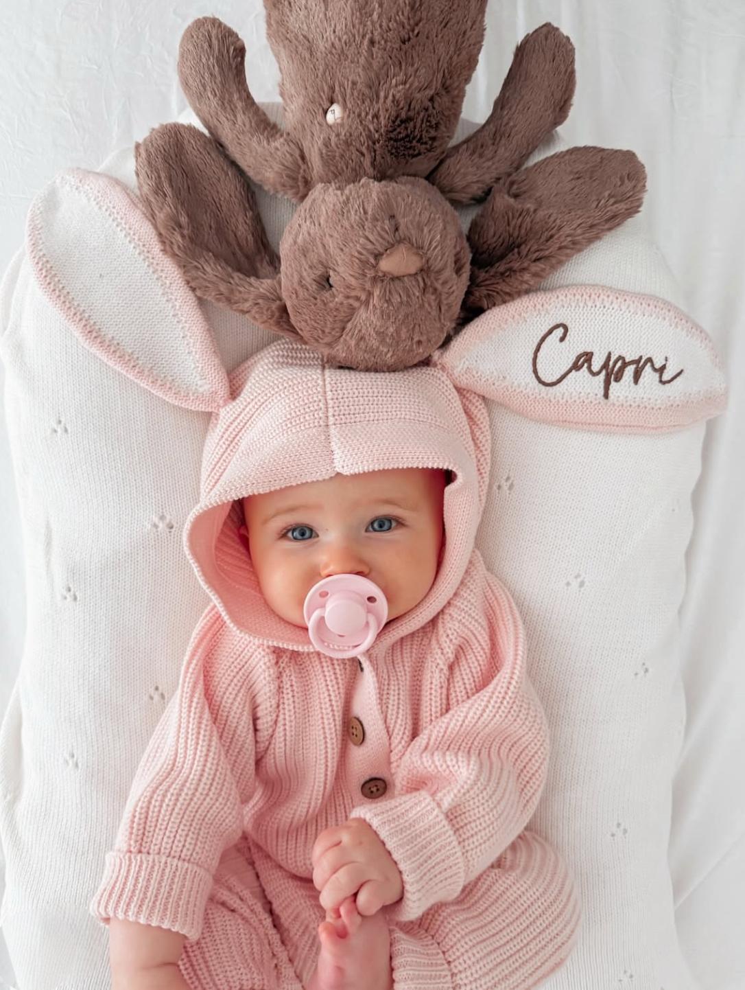 bimba che indossa la tutina in cotone organico rosa bunny soft rose di Mini Me con orecchie da coniglio